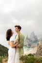 Young couple embracing and looking at each other, standing on coastline with beautiful view on ocean shore, vertical Royalty Free Stock Photo