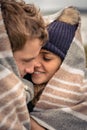 Young couple embracing outdoors under blanket in a Royalty Free Stock Photo