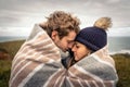 Young couple embracing outdoors under blanket in a cold day Royalty Free Stock Photo