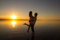 Young couple is embracing in the water on summer beach. Sunset over the sea.Two silhouettes against the sun. Just married couple