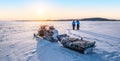 Young couple enjoy sunrise near snowmobile on frozen lake Inari in Finland, Lapland. Royalty Free Stock Photo