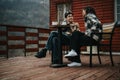 Young couple enjoying conversation with coffee on a cabin porch. Royalty Free Stock Photo