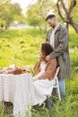 Young couple enjoying food and drinks in beautiful summer green park on romantic date picnic, handsome man and woman Royalty Free Stock Photo