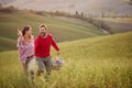 A young couple is enjoying nature while running a large meadow by holding hands. Relationship, love, together, picnic, nature Royalty Free Stock Photo