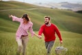 A young couple is enjoying nature while walking a large meadow by holding hands. Relationship, love, together, picnic, nature Royalty Free Stock Photo