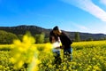Young couple enjoying smiling and kissing on a sunny spring day in a field of yellow flowers and blue sky Royalty Free Stock Photo