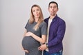 Young couple expecting a baby standing over white background making fish face with lips, crazy and comical gesture Royalty Free Stock Photo