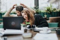 A young couple experiences surprise while viewing content on a laptop in a cozy cafe setting, reflecting shared Royalty Free Stock Photo