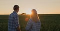 A young couple of farmers watch how a tractor works in the field. Stand side by side against the backdrop of a field of Royalty Free Stock Photo