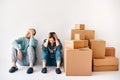 Young couple fell asleep after a moving day sitting on the floor surrounded by cardboard boxes Royalty Free Stock Photo