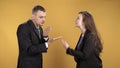 Young couple figuring things out cursing and gesticulating over yellow background.