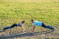 Young couple of fit sportsmen boy and girl doing exercise on green grass of public stadium outdoors Royalty Free Stock Photo