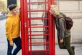 Young couple of friends near a classic British red phone booth Royalty Free Stock Photo