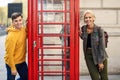 Young couple of friends near a classic British red phone booth Royalty Free Stock Photo