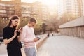 A young couple of friends, teenagers, students using mobile phones at city street Royalty Free Stock Photo