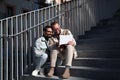 A young couple of gay men are sitting on the stairs with the laptop looking and pointing at the screen. The couple is having fun Royalty Free Stock Photo