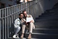 A young couple of gay men are sitting on the stairs with the laptop looking and pointing at the screen. The couple is having fun Royalty Free Stock Photo