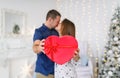 Young couple gently kiss in christmas decoration at home. Selective fokus in red box Royalty Free Stock Photo