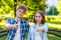 Young couple girl and boyfriend. In the summer in the park in nature. They sit on a bench in city. He gestures with his