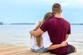 A young couple a girl and a young man sit on the beach in a Lotus position on a Wooden bridge and watch the sunset Royalty Free Stock Photo