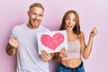 Young couple of girlfriend and boyfriend holding heart draw screaming proud, celebrating victory and success very excited with Royalty Free Stock Photo