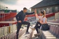 A young couple is giving five to each other while talking at the stadium and waiting for a training. Sport, athletics, athletes Royalty Free Stock Photo