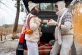 Young couple giving presents and looking each other sitting in the trunk in winter holidays. Royalty Free Stock Photo