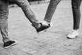 Young couple greeting with foot. Girl and guy bump feet outdoors. Foot shake style of greetings. Covid 19 prevention. People,