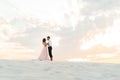 Young couple a guy in black breeches and a girl in a pink dress are walking along the white sand Royalty Free Stock Photo