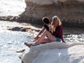 Young couple, a guy and a girl, sit on a rock, on the shores of the Mediterranean sea, and look out to sea in Nahatiya, Israel Royalty Free Stock Photo