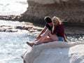 Young couple, a guy and a girl, sit on a rock, on the shores of the Mediterranean sea, and look out to sea in Nahatiya, Israel Royalty Free Stock Photo