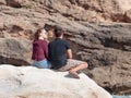 Young couple, a guy and a girl, sit on a rock, on the shores of Royalty Free Stock Photo