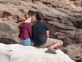Young couple, a guy and a girl, sit on a rock, on the shores of Royalty Free Stock Photo