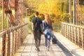 Young couple:the guy and the girl walk on the bridge in the fall holding hands. Romatic relations between a man and a woman. The Royalty Free Stock Photo