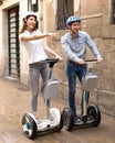 Young couple guy and girl walking on segway in streets of european city Royalty Free Stock Photo