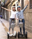 Young couple guy and girl walking on segway in streets of european city Royalty Free Stock Photo