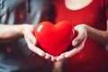 young couple hands hold red heart