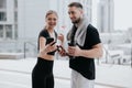 Young couple handsome brunette man and beautiful woman in sportswear check smartphone drink water having rest during Royalty Free Stock Photo