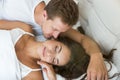 Young couple handsome husband kissing his beautiful sleeping wife in bed in bright bedroomfeeling happy family morning