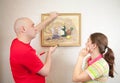 Young couple hanging art picture on wall at