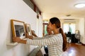 Young couple hanging picture frame on wall in their new house. Smiling husband and wife happy settling together in new Royalty Free Stock Photo