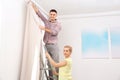 Young couple hanging window curtain indoors Royalty Free Stock Photo