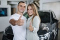 Young couple happy after buying new car from car showroom. Man and woman give thumb up. Focus on hands Royalty Free Stock Photo