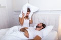Young couple have problem with man`s snoring. Heterosexual couple in bed, man sleeps and snoring with mouth open, while a tired Royalty Free Stock Photo