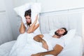 Young couple have problem with man`s snoring. Heterosexual couple in bed, man sleeps and snoring with mouth open, while a tired Royalty Free Stock Photo