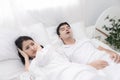 Young couple have problem with man`s snoring. Heterosexual couple in bed, man sleeps and snoring with mouth open, while a tired Royalty Free Stock Photo