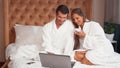 Young couple having coffee in bed while using laptop Royalty Free Stock Photo