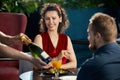 Young couple having dinner in restaurant. Waiter brought a bottle of champagne Royalty Free Stock Photo