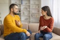 Young Couple Having Emotional Conversation While Sitting On Couch At Home Royalty Free Stock Photo