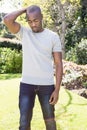 African American man standing on backyard lawn surrounded by flowering bushes and trimmed hedges Royalty Free Stock Photo